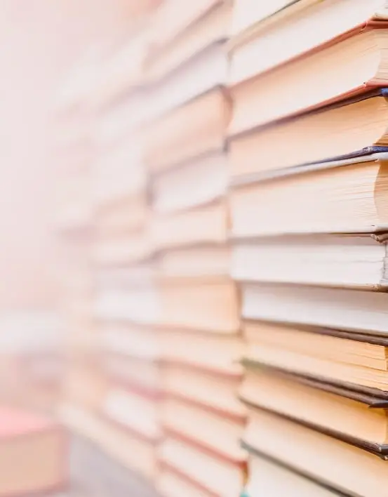 A stack of colorful books neatly arranged on a wooden table, inviting readers to explore their contents. The Novel View's Contact Me page photo.
