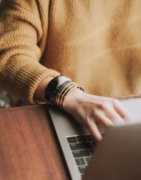 A woman focused on editing text while typing on a laptop at her desk, surrounded by a tidy workspace. The Novel View's Services Page image.